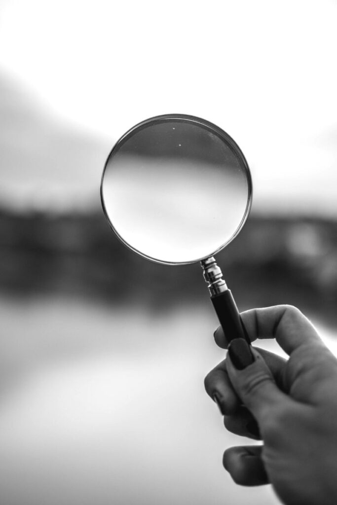 hand holding a magnifying glass up to a landscape 1